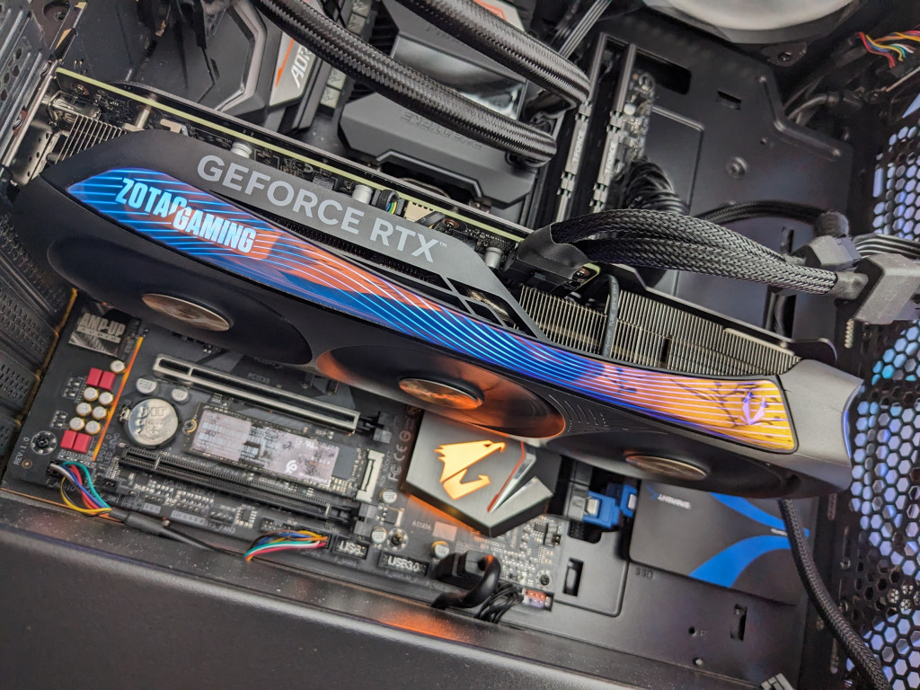 View of the ZOTAC GAMING GeForce RTX 4070 AMP Airo in a PC, powered up with the fans spinning.