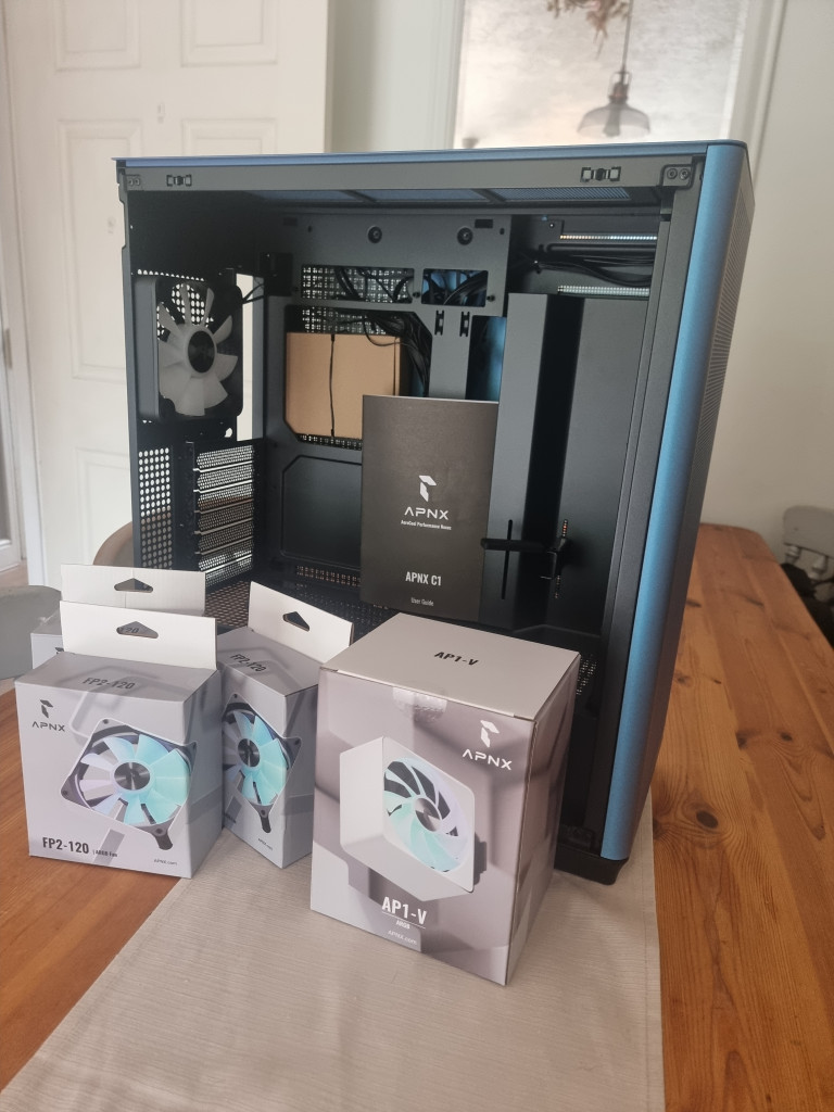 photo showing the chromaflair coloured pc case sitting on a wooden table with the boxed FP2 and AP1 fans infront of it.