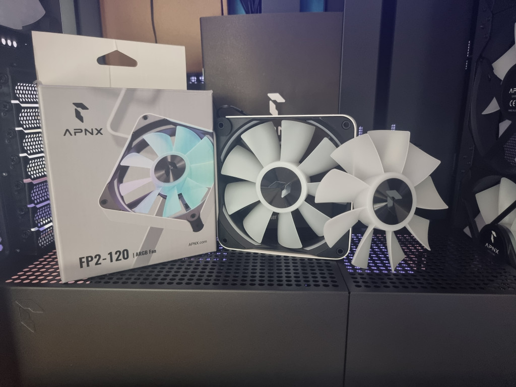 photo showing the FP2 white 120mm pwm fan sitting on show within the pc case alongside the box it was shipped in. There is also a separate reversible blade in the shot.