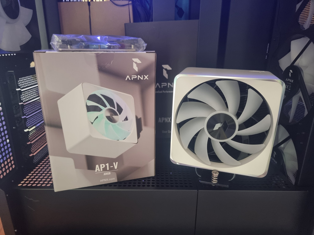 photo showing the white ap1-v cpu cooler fan sitting on show within the pc case alongside the box that it came in.