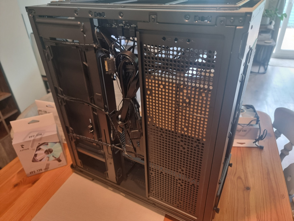 photo showing the side of the pc case that hides away all of the wiring. A black mesh panel alongside a bundle of tied up black cables can be seen.