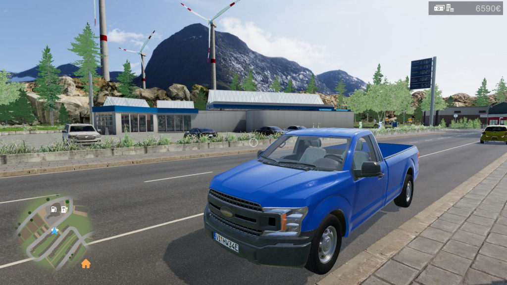 A blue pickup truck is parked at the side of a road with a mountainous landscape in the background